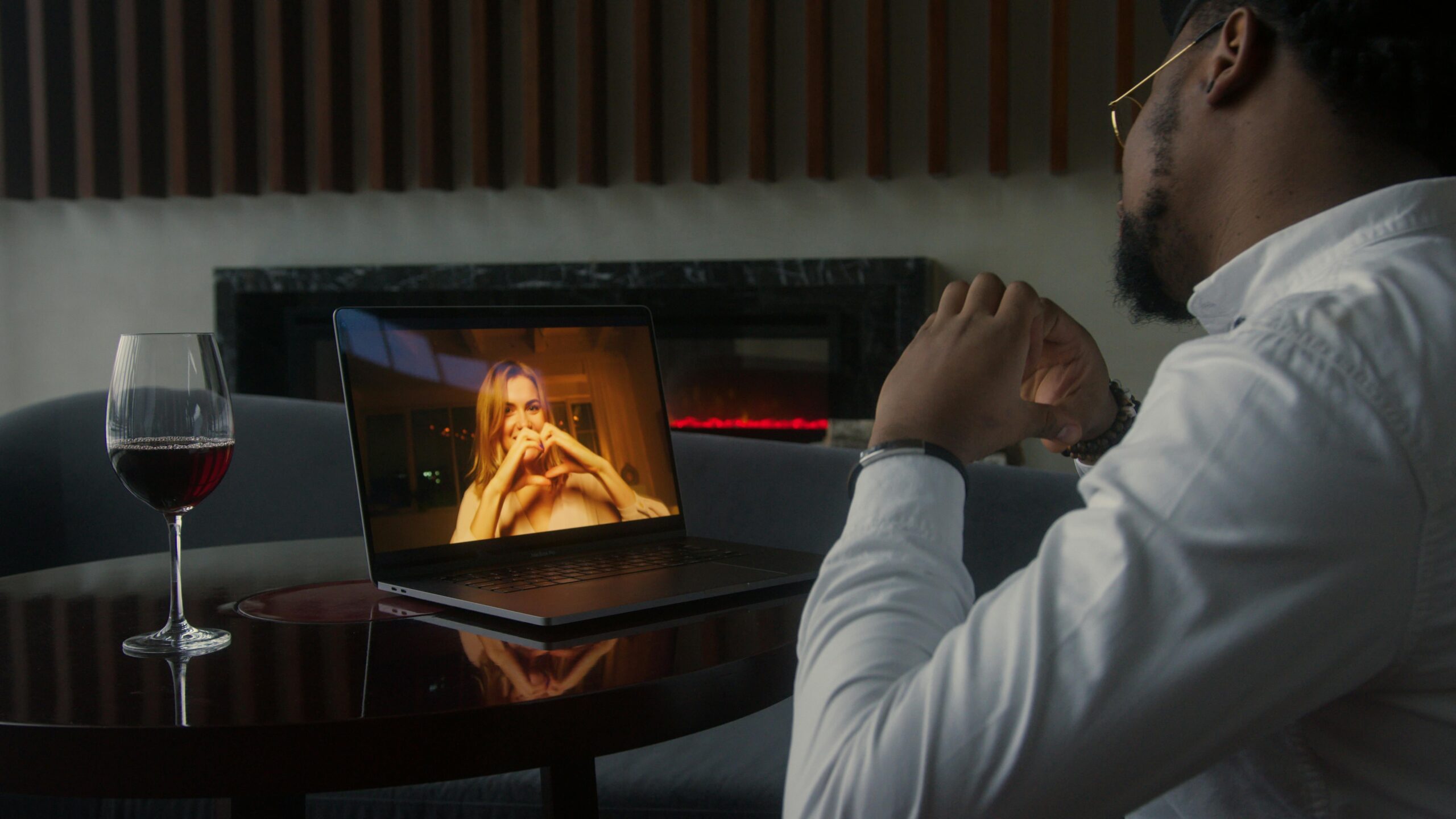 Man enjoying his AI companion while he's well dressed sipping a wine as if he was on a date with a gorgeous model.