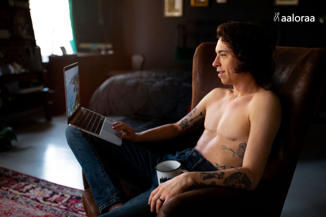 Stud with his shirt off on his laptop about to jump onto the best porn site ThePornBlender